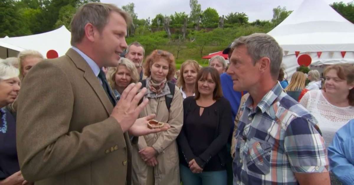 Screenshot showing the expert holding the set of false teeth, and the guest (Cover image source: Antiques Roadshow/BBC One)