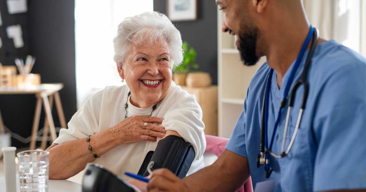 Representative image of a male caregiver measuring blood pressure to senior woman (Cover image source: Getty Images/Stock photo by Halfpoint Images)