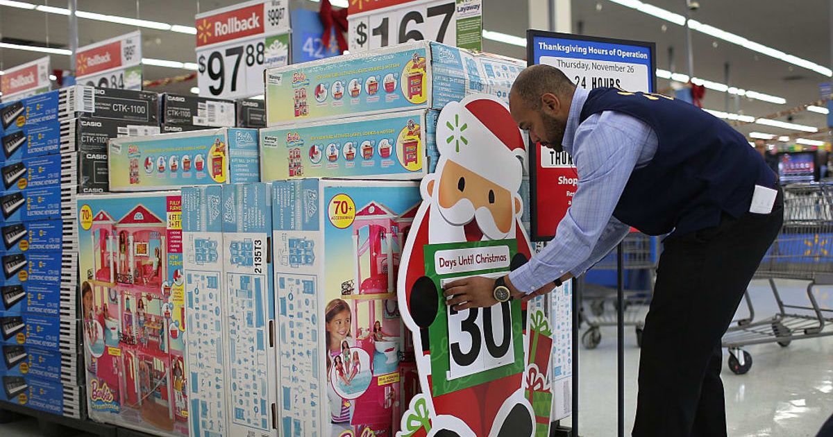 Walmart worker fixing a Christmas poster (Cover Image Source: Getty Images | Photo by Joe Raedle)