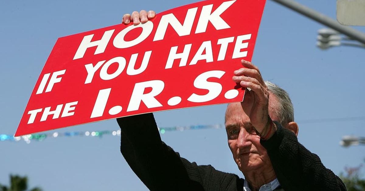 Representative image of a protestor encouraging motorists to express their anger at the Internal Revenue Service (IRS)(Cover image source: Getty Images/Photo by David McNew)