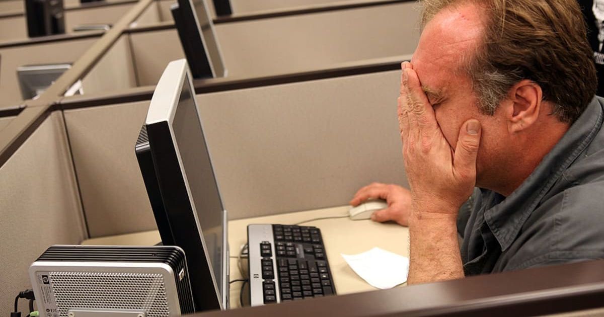Man wipes his eyes as he uses a computer to fill out paperwork (Cover image source: Getty Images | Photo by Justin Sullivan)