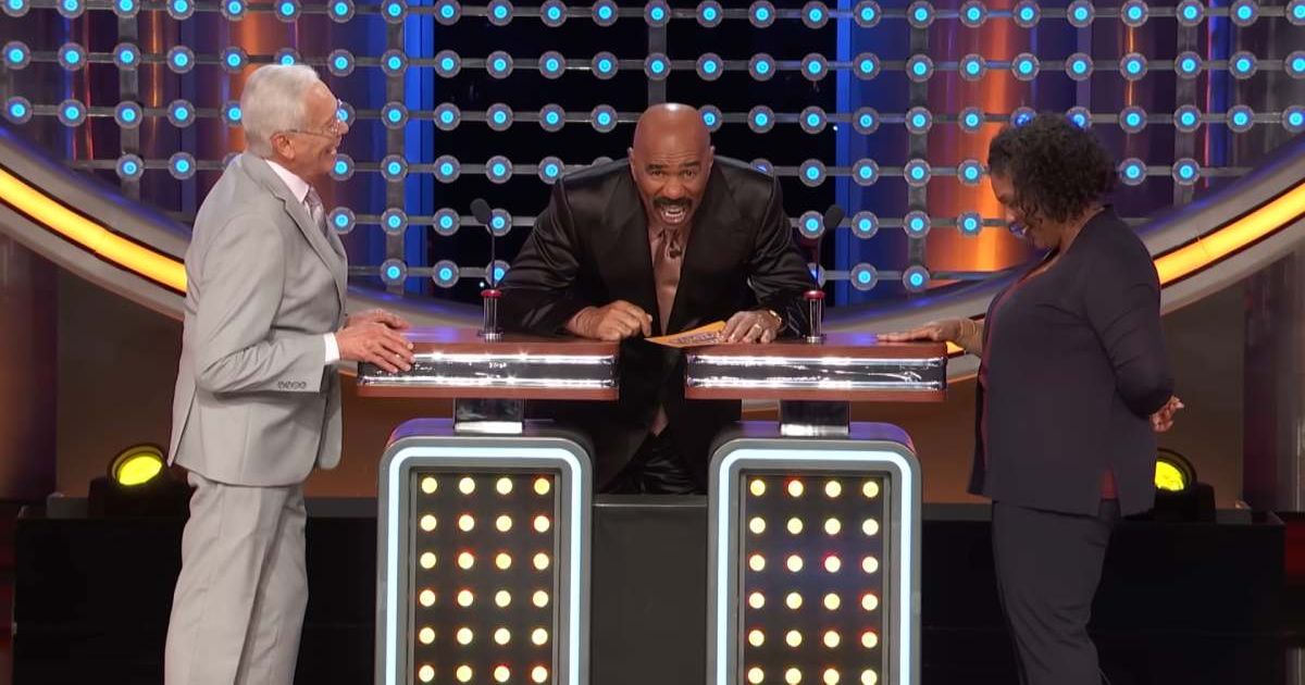 Screenshot showing Harvey laughing at an answer at the podium (Cover image source: YouTube/Family Feud)