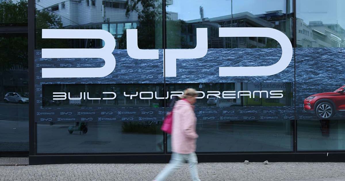 Representative image of a woman walking past a dealership of Chinese electric car manufacturer BYD (Image source: Getty Iamges/Photo by Sean Gallup)