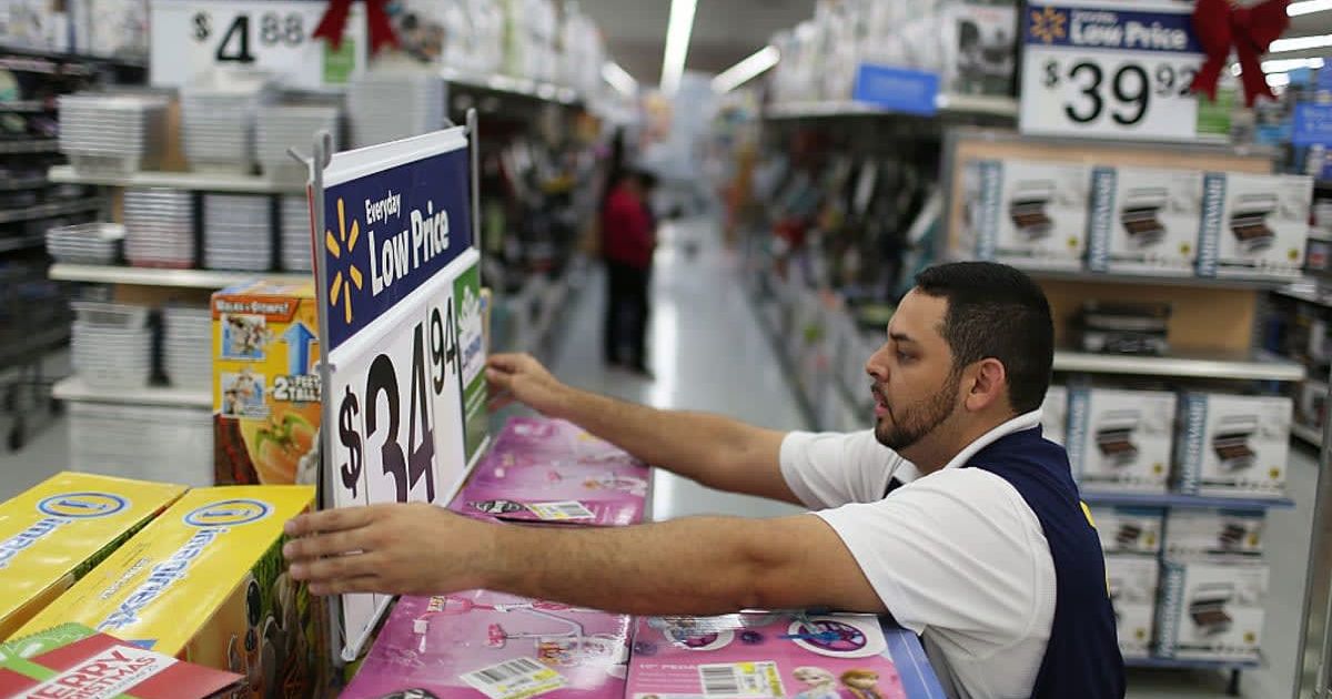 Walmart employee fixing a display (Image Source: Getty Images | Photo by Joe Raedle) 