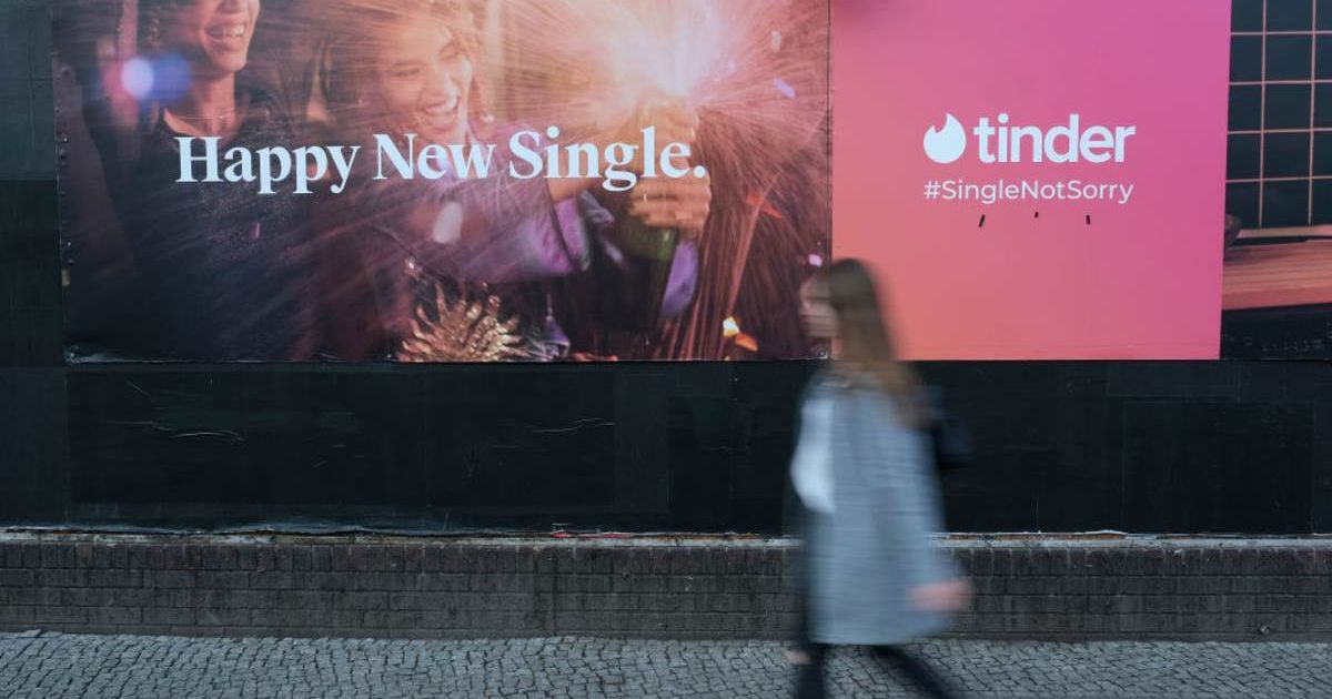 Representative image of a young woman walking past a billboard advertisement for the dating app Tinder (Cover image source: Getty Images/Photo by Sean Gallup)